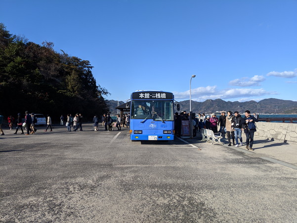 大久野島の港で無料送迎バスに乗る観光客