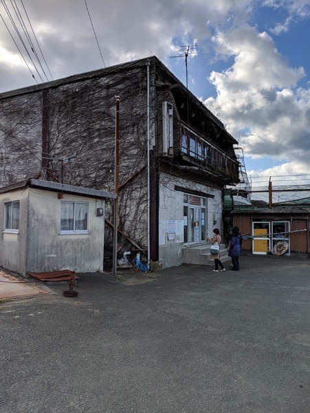 青島行きの欠航案内が掲示される建物前で外国人観光客が途方に暮れる